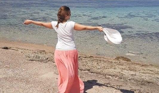 Donna abbraccia aperte in riva ala mare